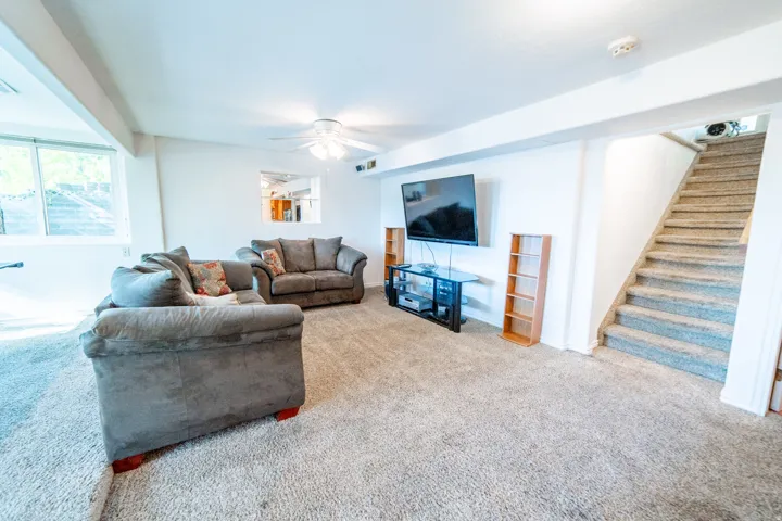 Carpeted interior space featuring white walls and a ceiling fan