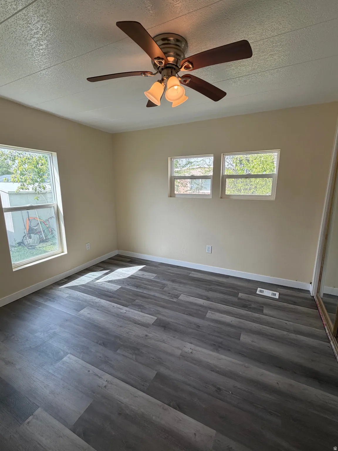 Room featuring wood-finish flooring, neutral wall tones, and multiple windows