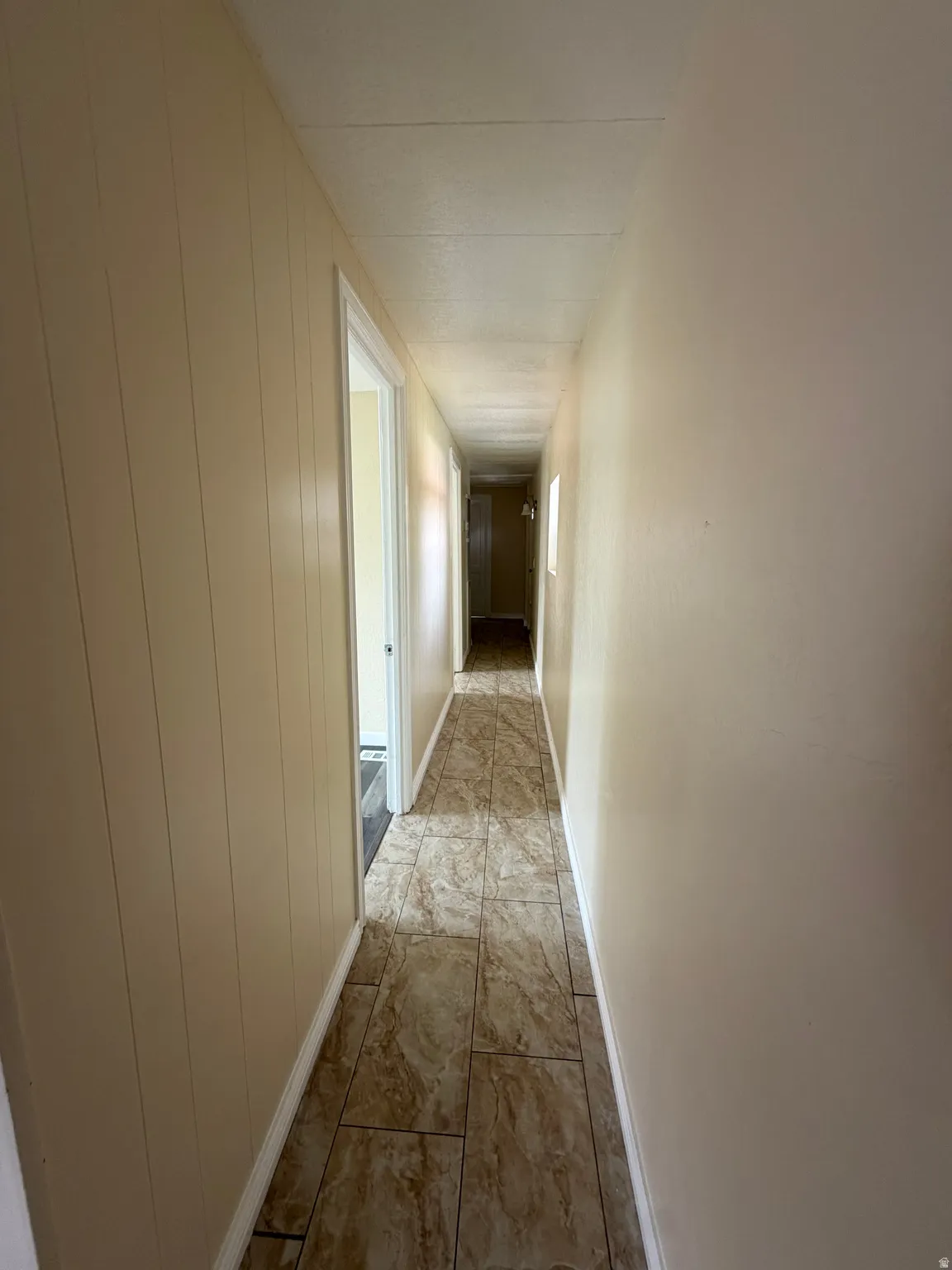 Hallway featuring neutral-toned walls, tile flooring, and white trim