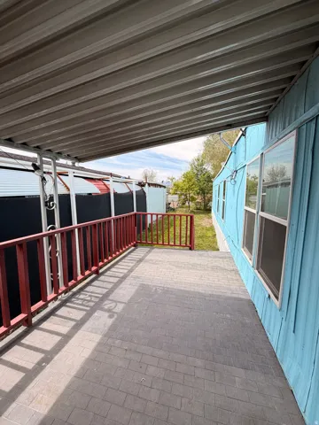 Covered patio area featuring a corrugated metal roof and brick-look flooring