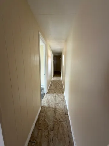 Hallway featuring neutral-toned walls, tile flooring, and white trim