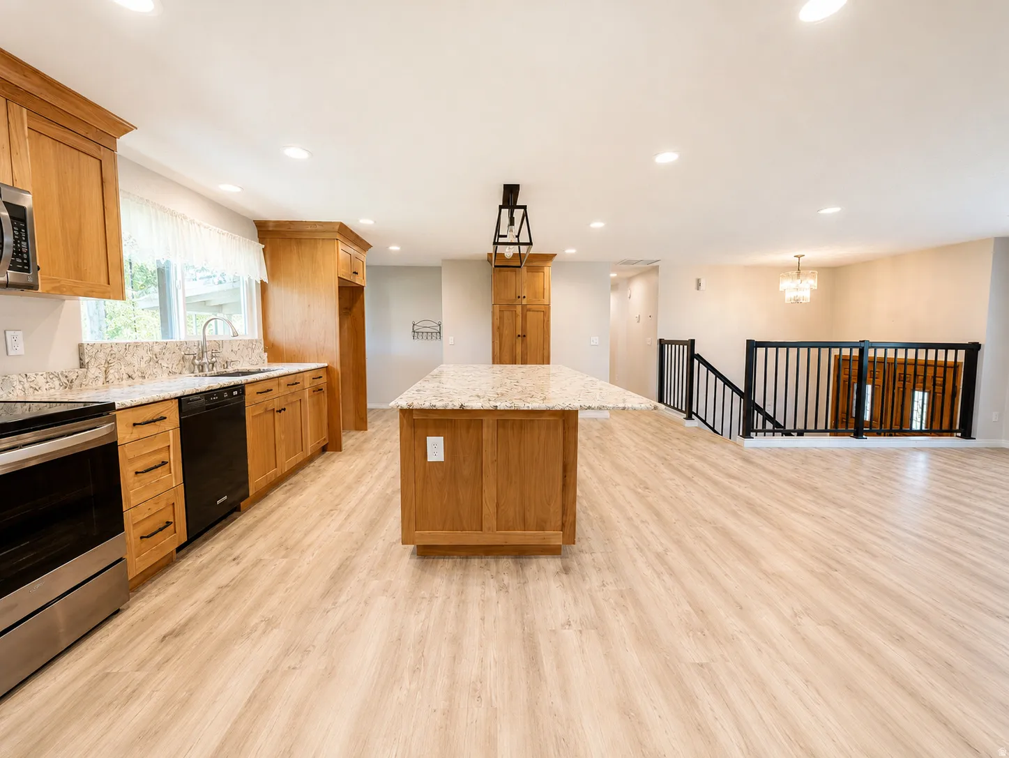 Kitchen featuring light wood cabinetry with black hardware, granite countertops, and stainless steel appliances