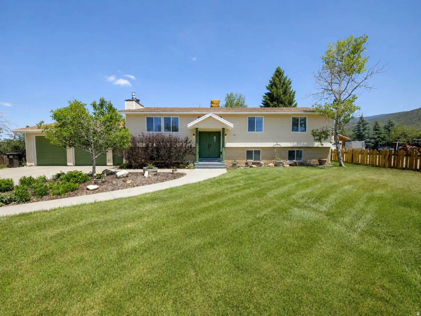 Light-colored exterior with a green front door and garage doors