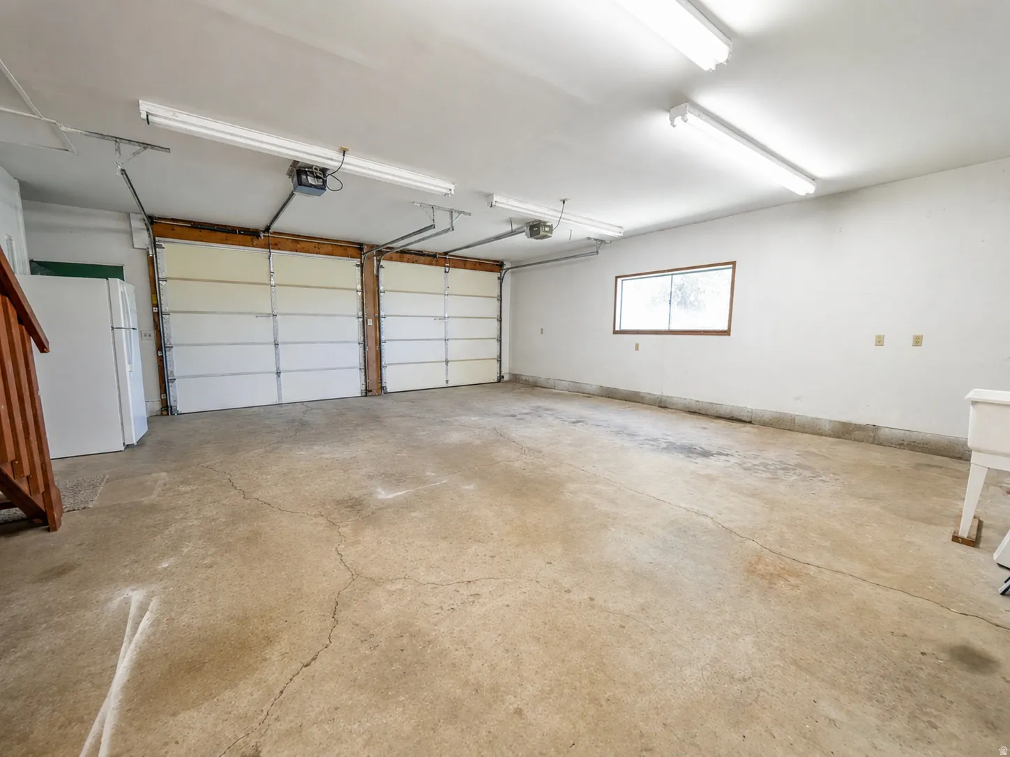 Two-car garage featuring concrete flooring, white paneled garage doors, and a single window for natural light