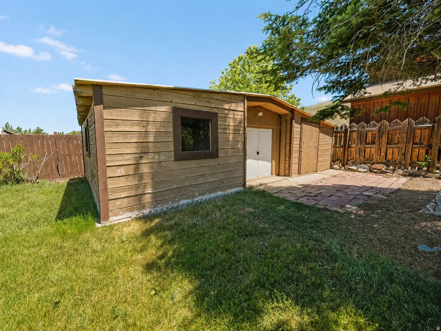 Wood-sided storage shed with a gambrel roof and double white doors