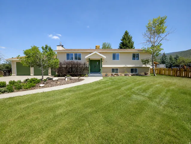 Light-colored exterior with a green front door and garage doors
