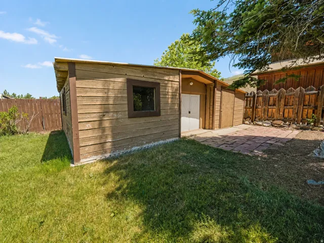 Wood-sided storage shed with a gambrel roof and double white doors