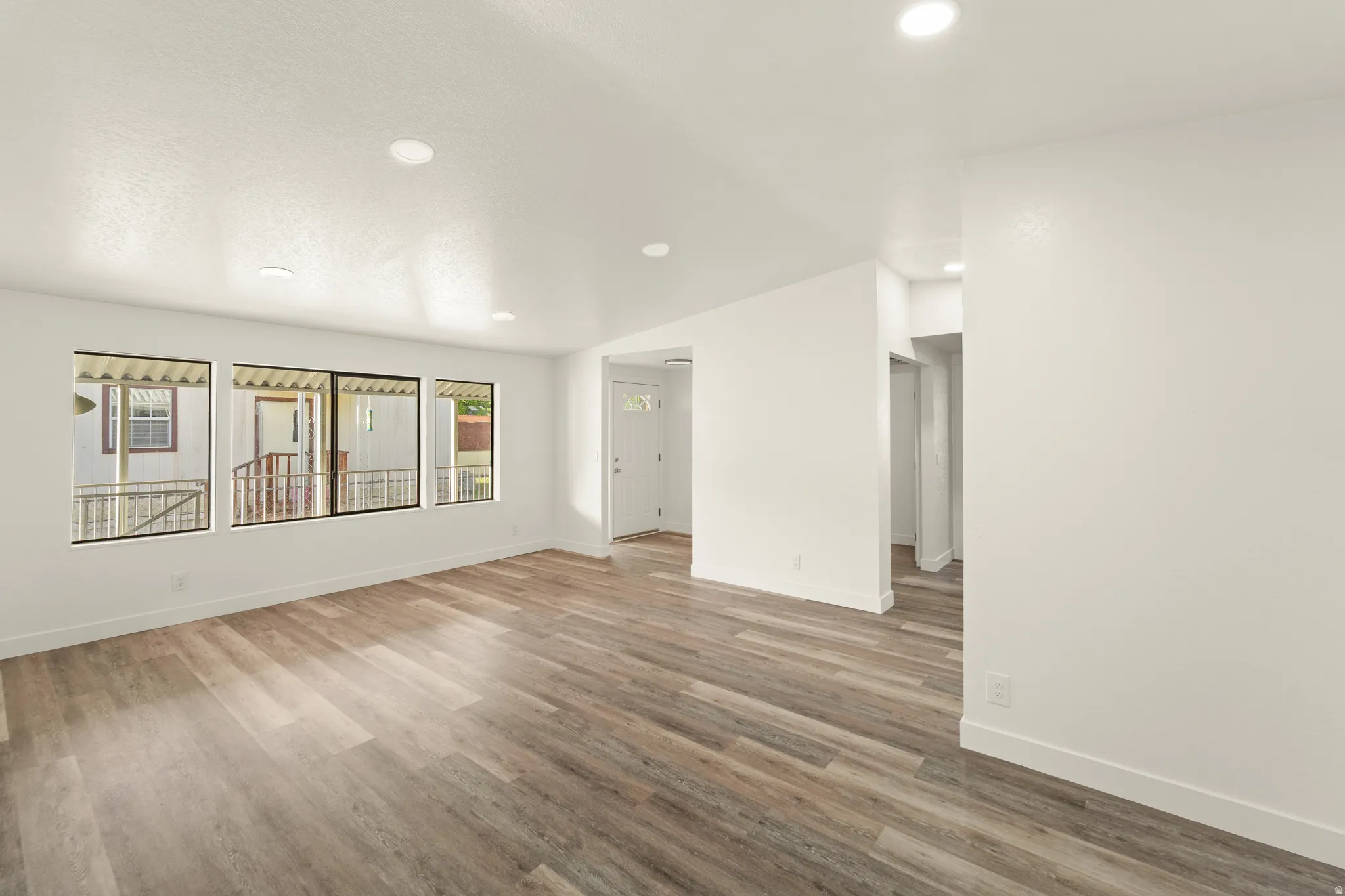 Spacious interior featuring wood-finish flooring, recessed ceiling lighting, and multiple windows