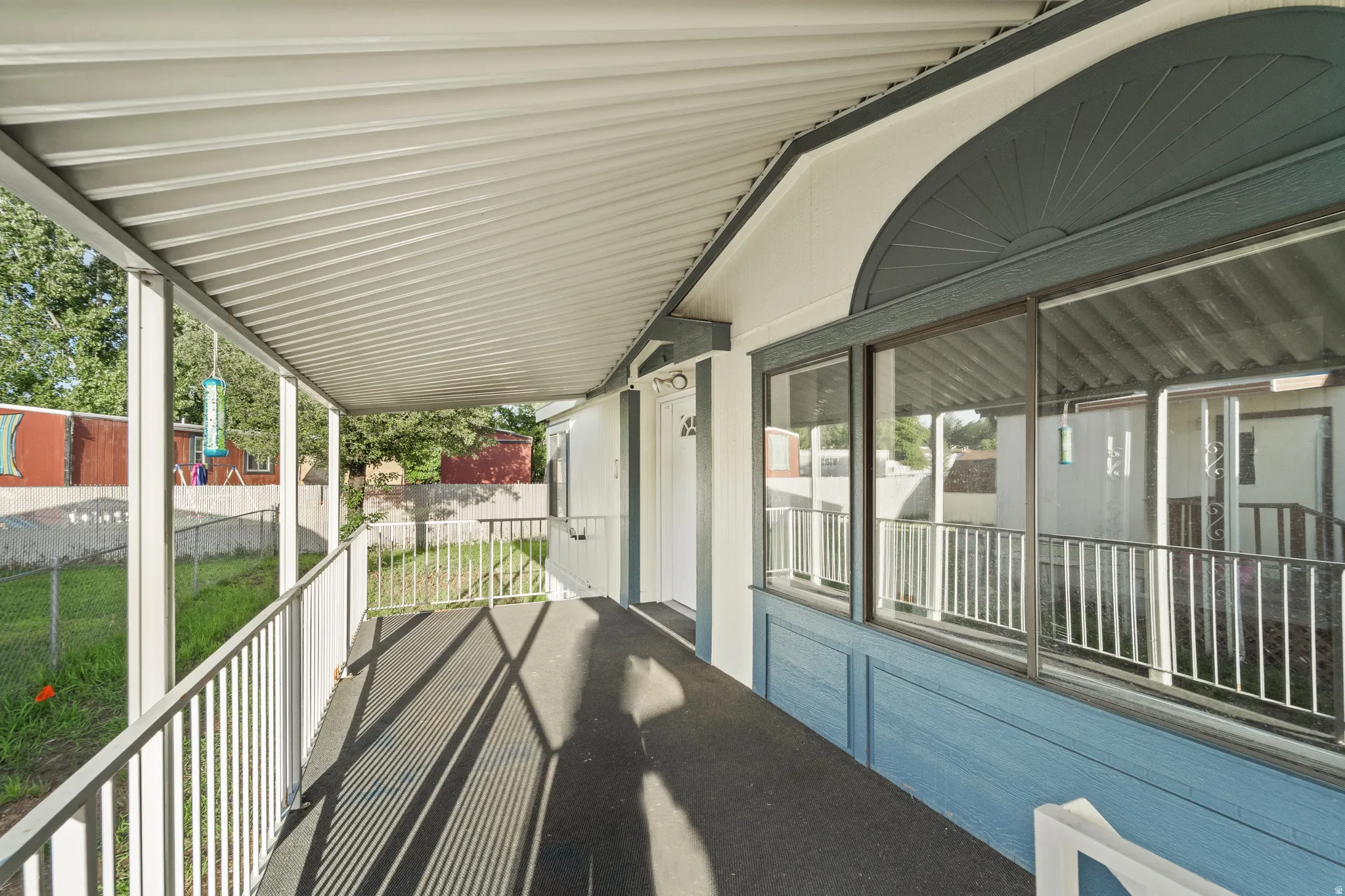 Covered porch with white metal railings and a corrugated metal roof