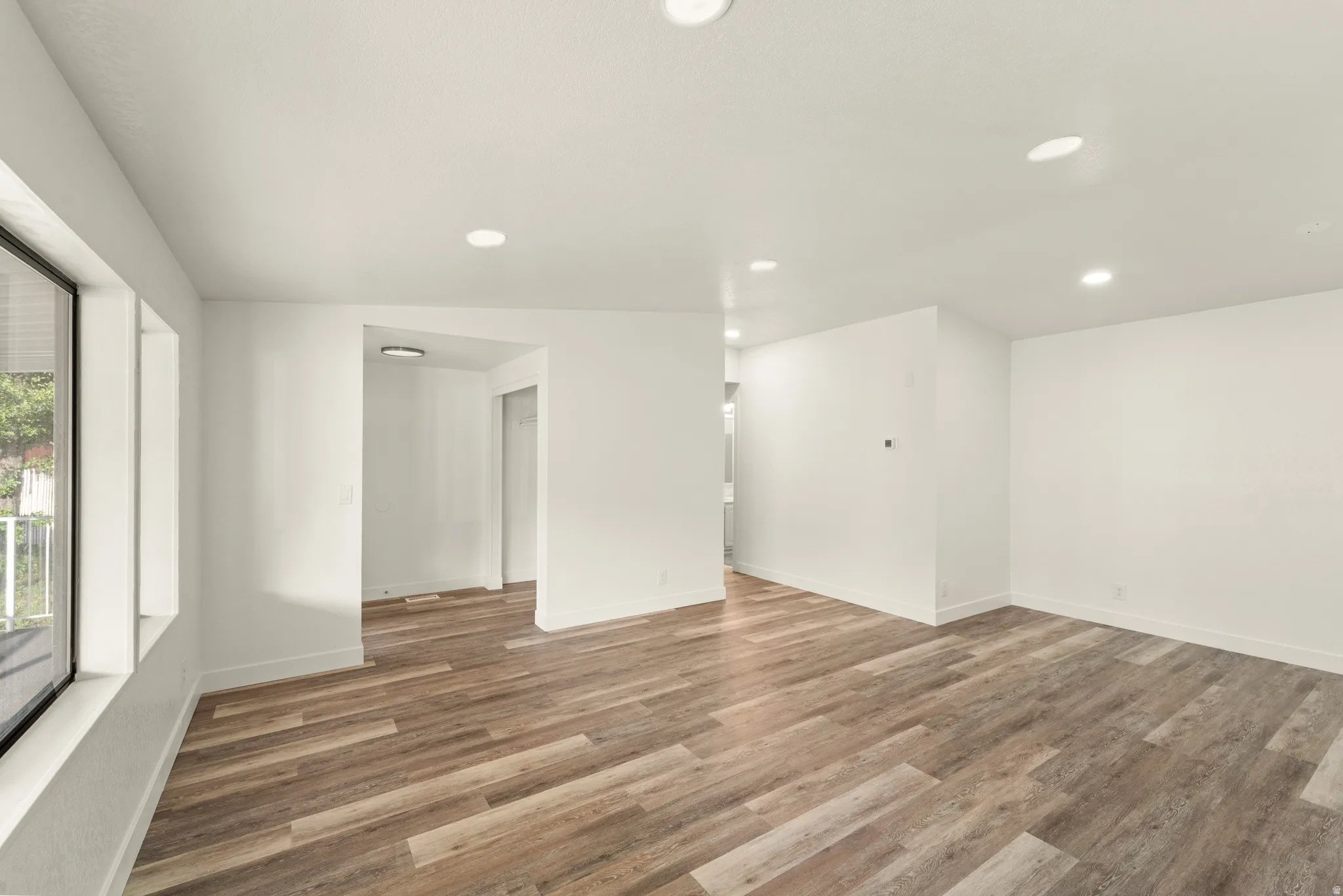 Open concept interior featuring wide plank wood-finish flooring, recessed lighting, and large windows
