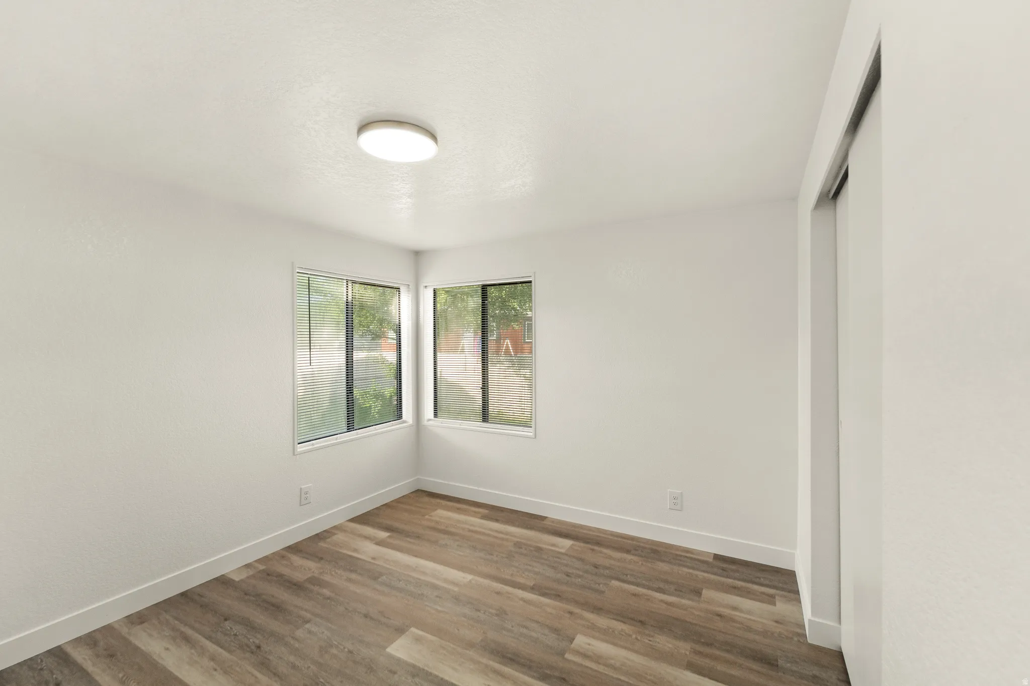 Room featuring wood-finish flooring, white baseboards, and neutral wall paint
