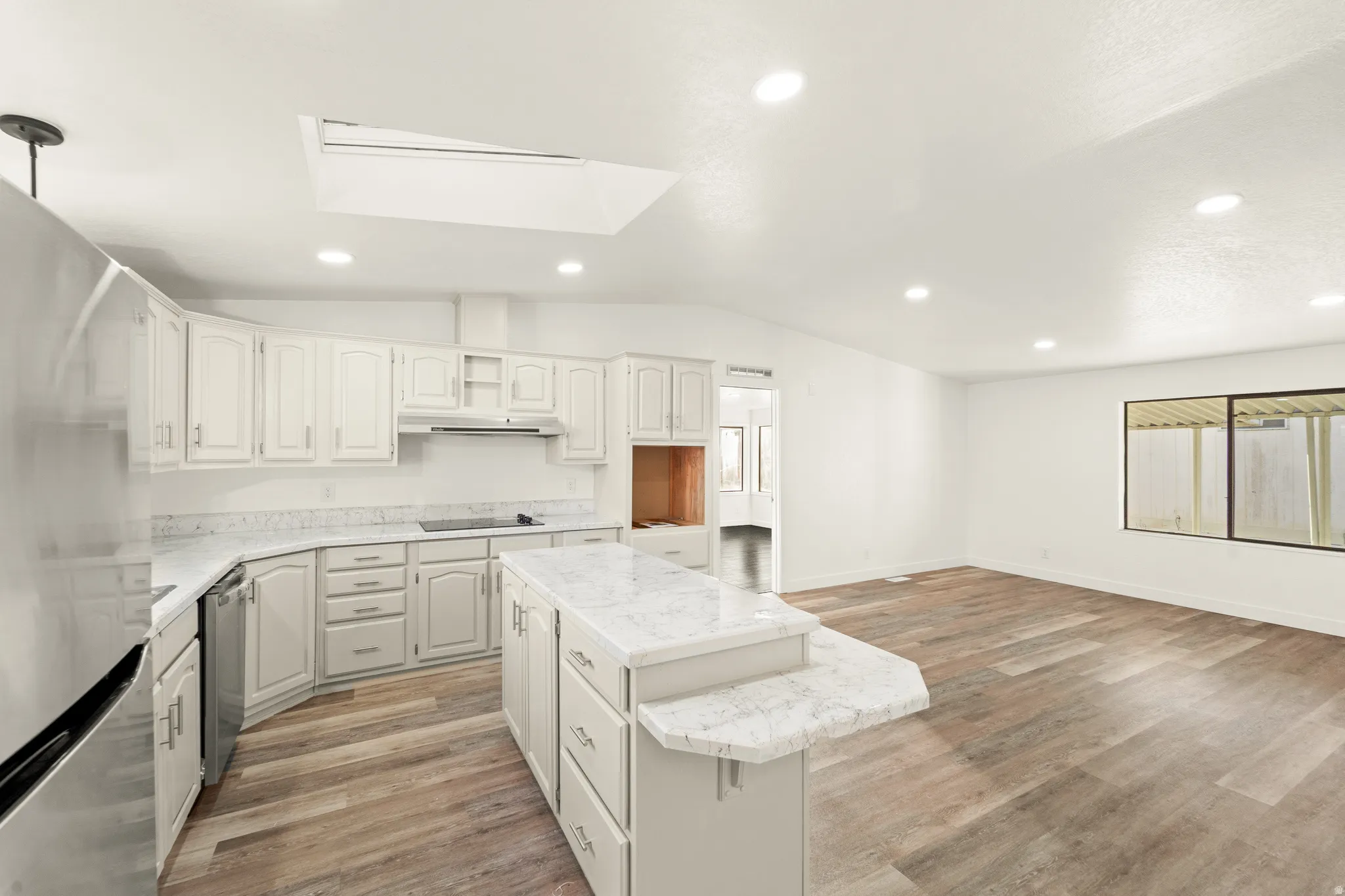 Open-concept kitchen featuring white cabinetry, light-toned countertops, and stainless steel appliances