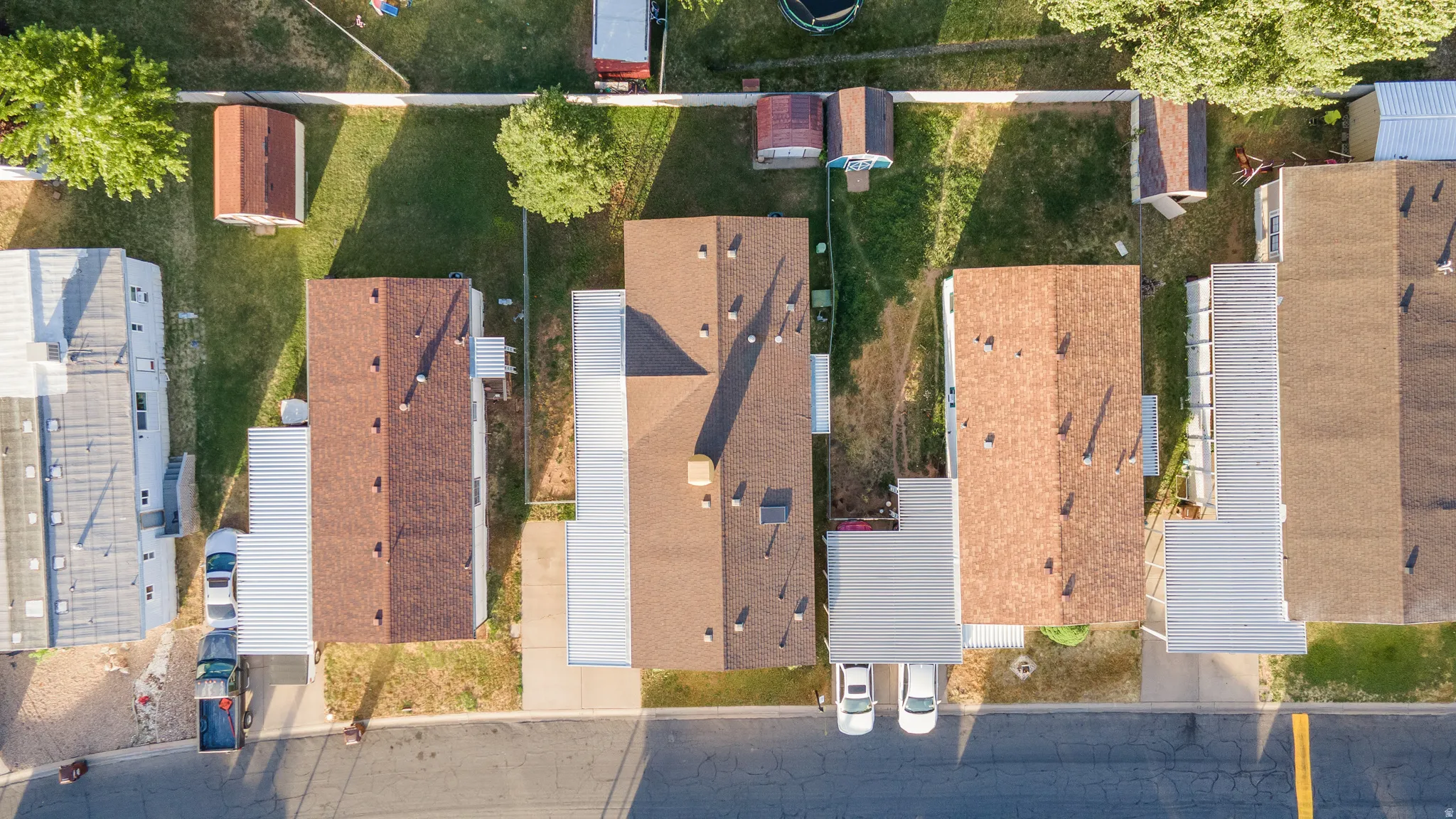 Aerial view showcasing three residential properties with brown shingle roofing
