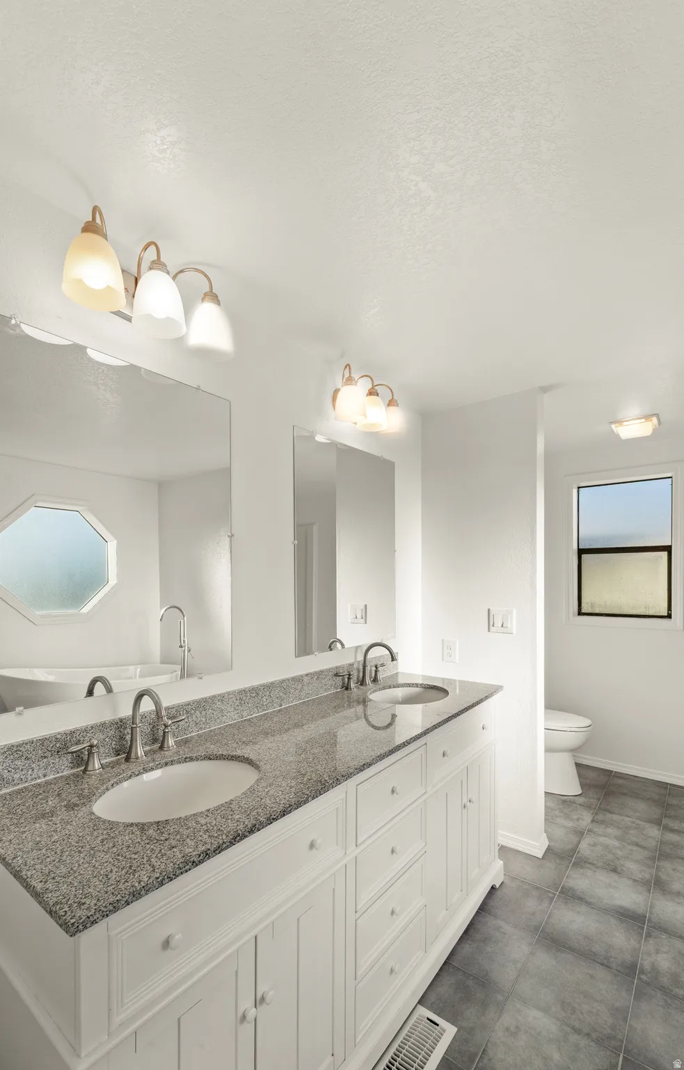 Spacious bathroom featuring a double vanity with granite countertop and integrated sinks