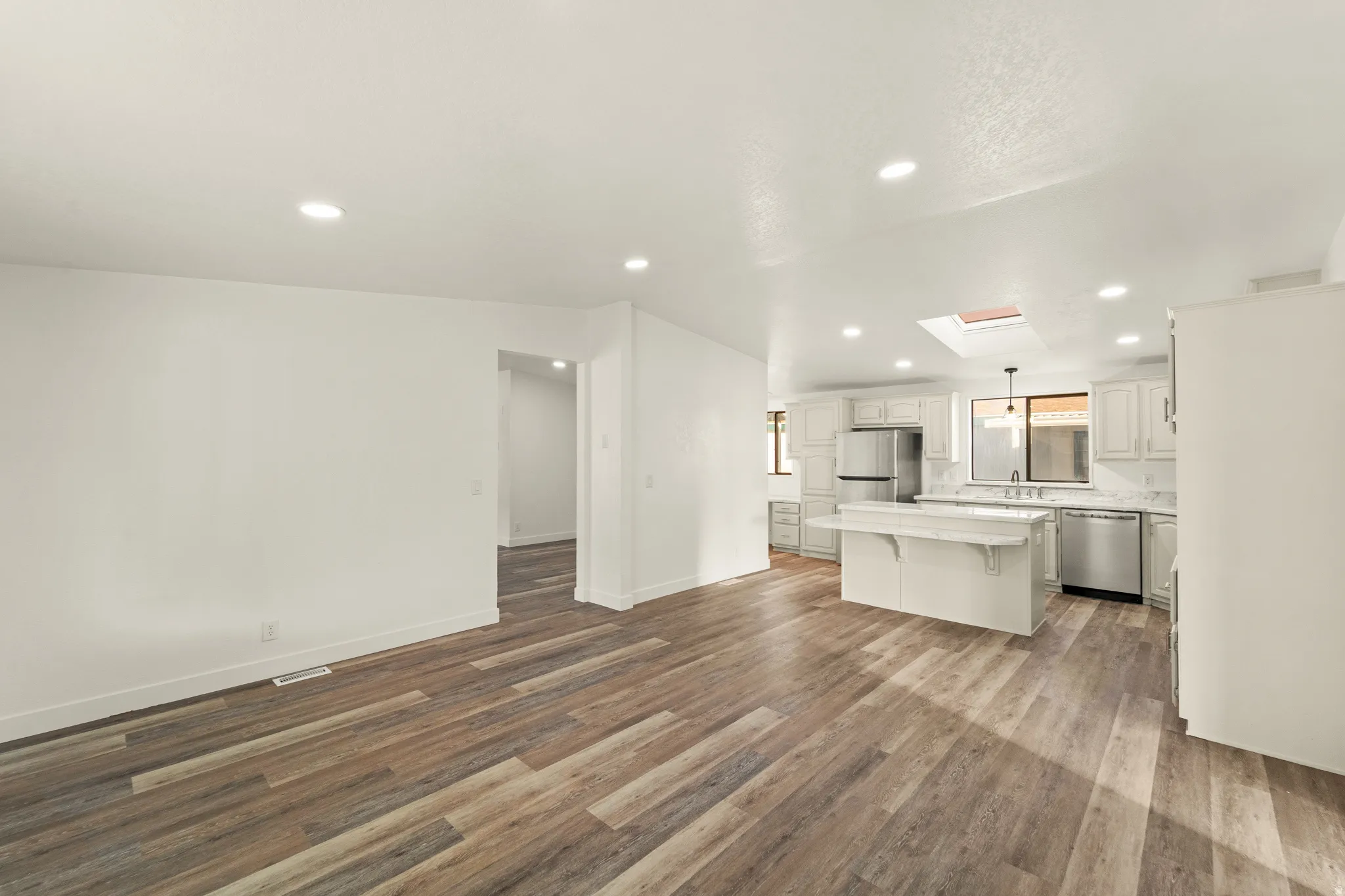 Open-concept living space featuring wood-finish flooring and recessed lighting