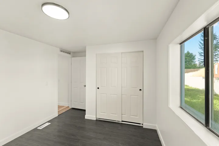 Room featuring dark wood-finish flooring, white walls, and a large window
