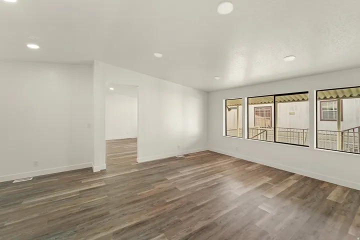 Spacious room featuring wood-finish flooring, recessed lighting, and multiple large windows
