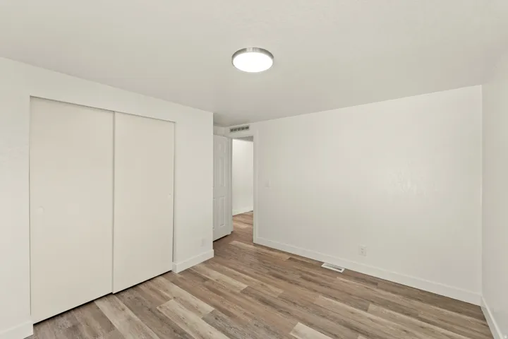 Interior room featuring wood-finish flooring, white baseboards, and a flush-mount ceiling light fixture