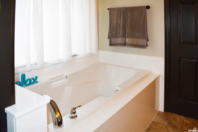 Bathtub featuring a deck-mounted chrome faucet and white surround