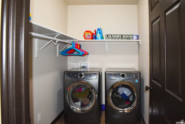 Dedicated laundry space featuring a white mounted shelf, hanging rod, and light beige walls