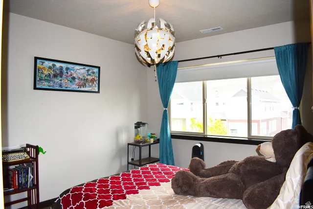 Bright room featuring a large window with white roller shades, a modern spherical pendant light fixture, and light-toned walls
