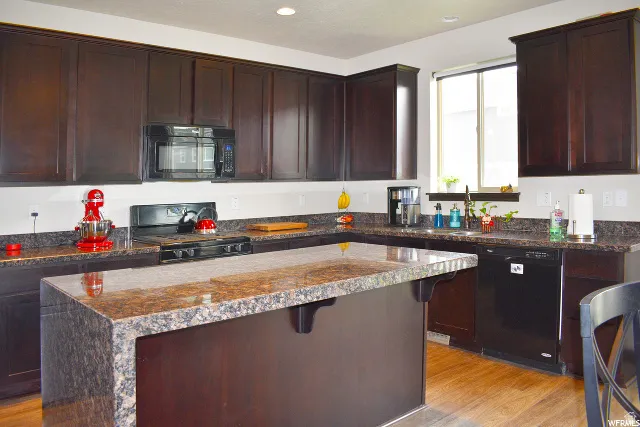 Kitchen featuring dark wood-finish cabinetry, granite countertops, and wood-finish flooring