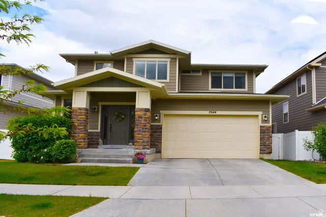 Contemporary two-story residence featuring a neutral-toned exterior with stone accents, a prominent front porch with substantial columns, and a two-car garage with a light-colored door