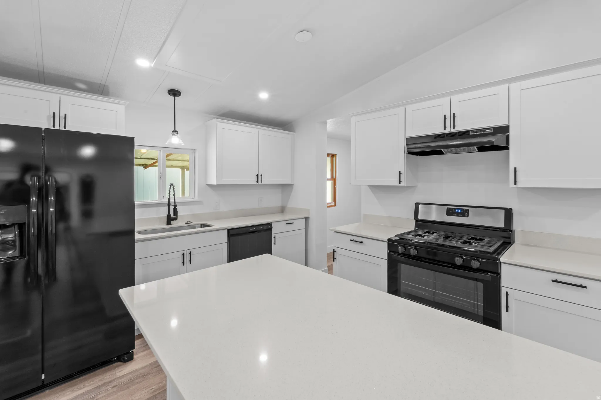 Modern kitchen featuring white shaker cabinetry, light-toned countertops, and a central island