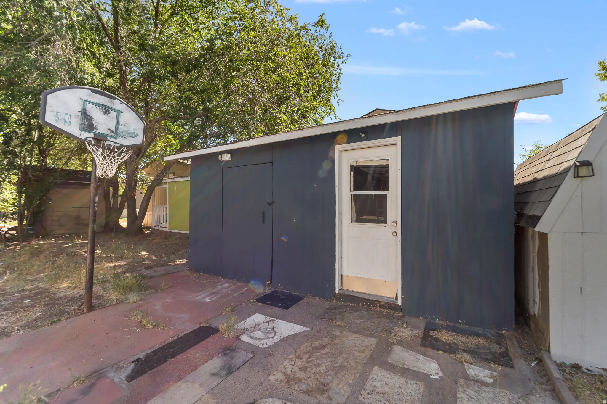 Outdoor storage structure with dark-toned siding and a white entry door