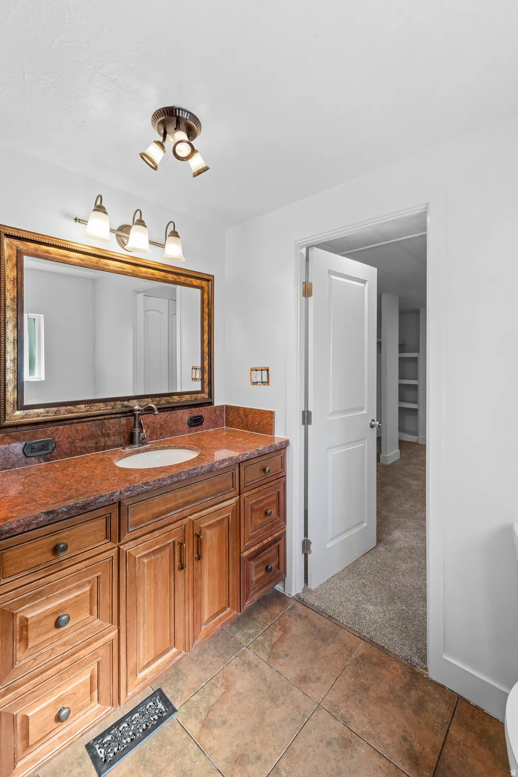 Bathroom vanity featuring a single basin, bronze-finish faucet, and an ornate framed mirror