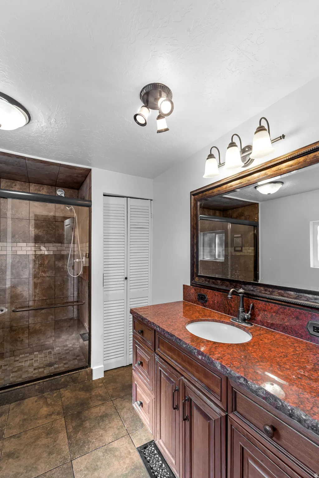 Spacious bathroom featuring a double vanity with a red granite countertop and an undermount sink