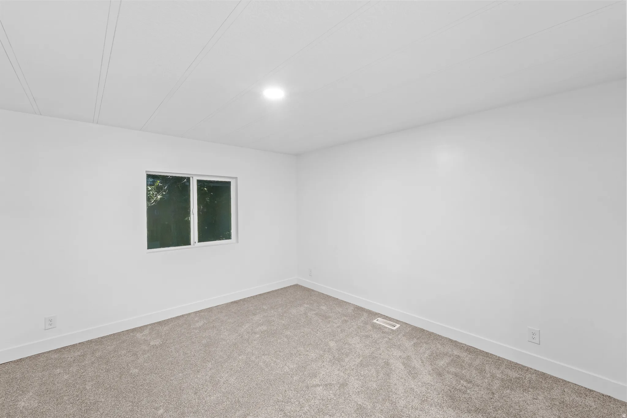 Bright room featuring a window with white trim, fresh white walls, and a new carpeted floor