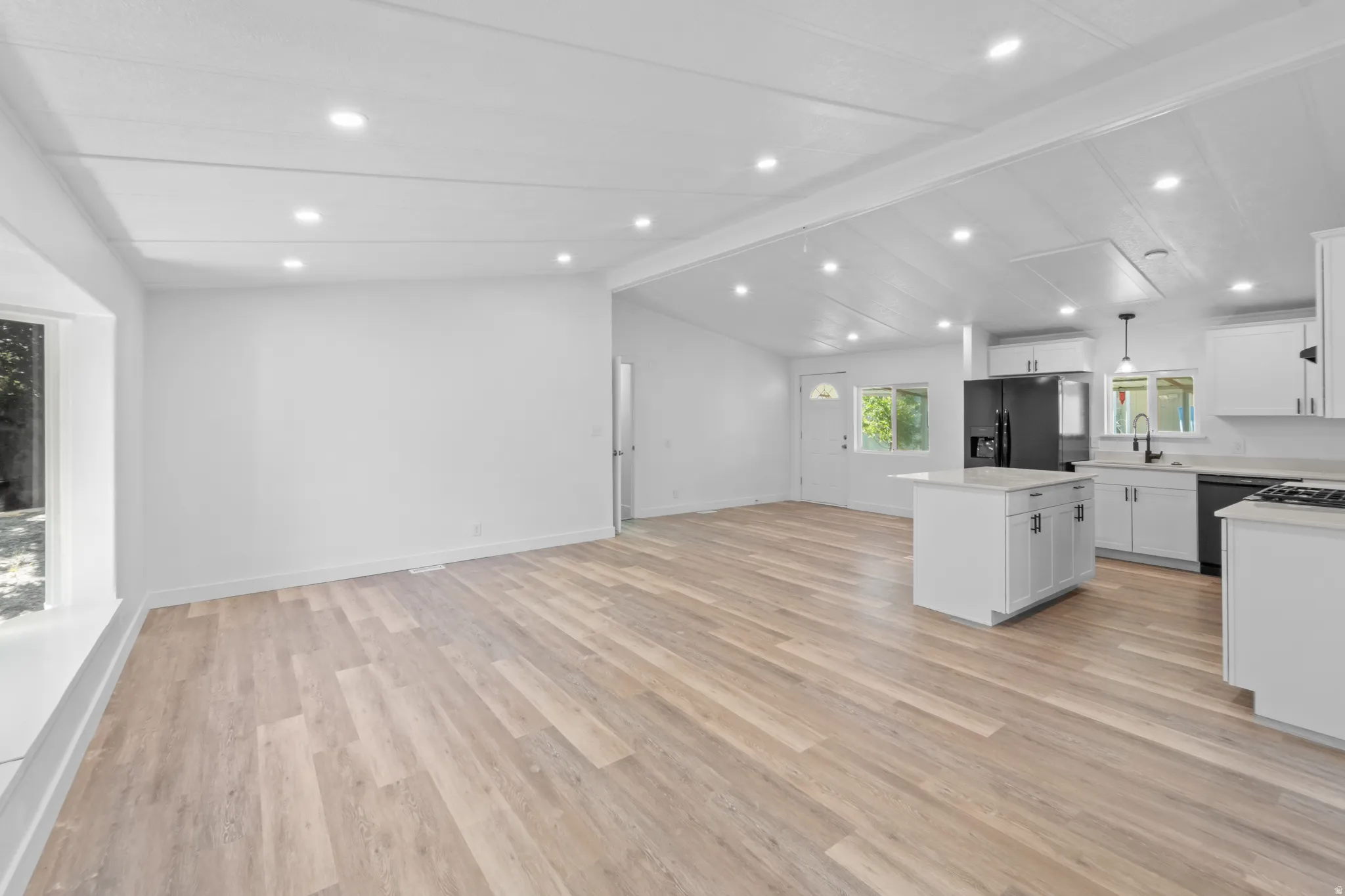 Open-concept living area featuring wood-finish flooring, recessed lighting, and a white color palette