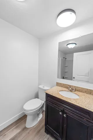 Bathroom featuring a dark wood-finish vanity with a light-toned stone countertop, an undermount sink, and a framed mirror