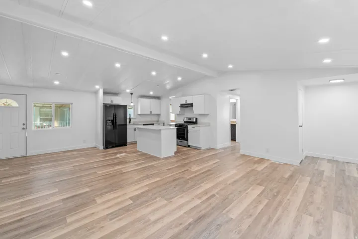 Open-concept living space featuring wood-finish flooring, recessed lighting, and a vaulted ceiling