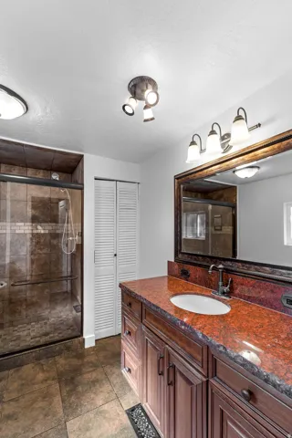 Spacious bathroom featuring a double vanity with a red granite countertop and an undermount sink