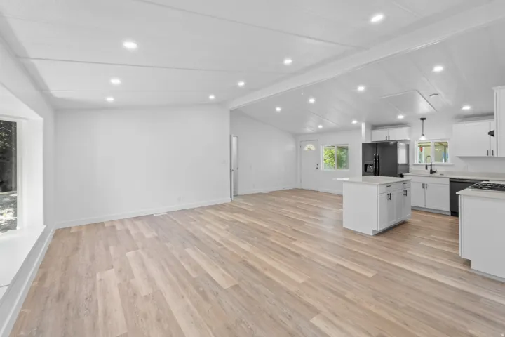 Open-concept living area featuring wood-finish flooring, recessed lighting, and a white color palette