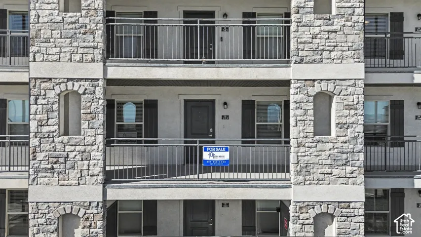 Multi-story exterior featuring stacked stone veneer, decorative arched masonry niches, and integrated metal balcony railings