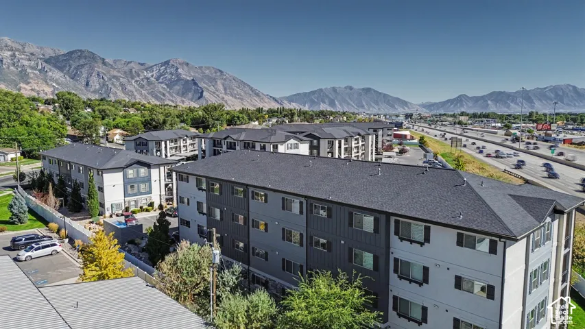 Multi-story residential complex featuring dark-toned board and batten siding, high-pitch rooflines, exterior balconies, and a mountain backdrop