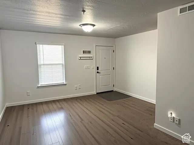 Entry area featuring wood-finish flooring, a white paneled door with contemporary hardware, and a window with horizontal blinds
