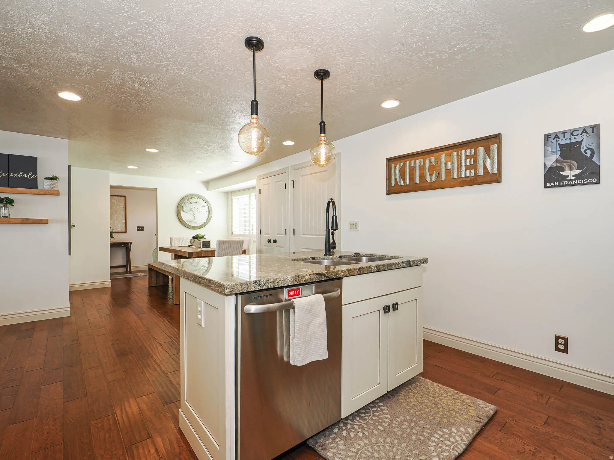 Kitchen island featuring a double-basin sink with a matte black faucet, integrated dishwasher, and granite-style countertop