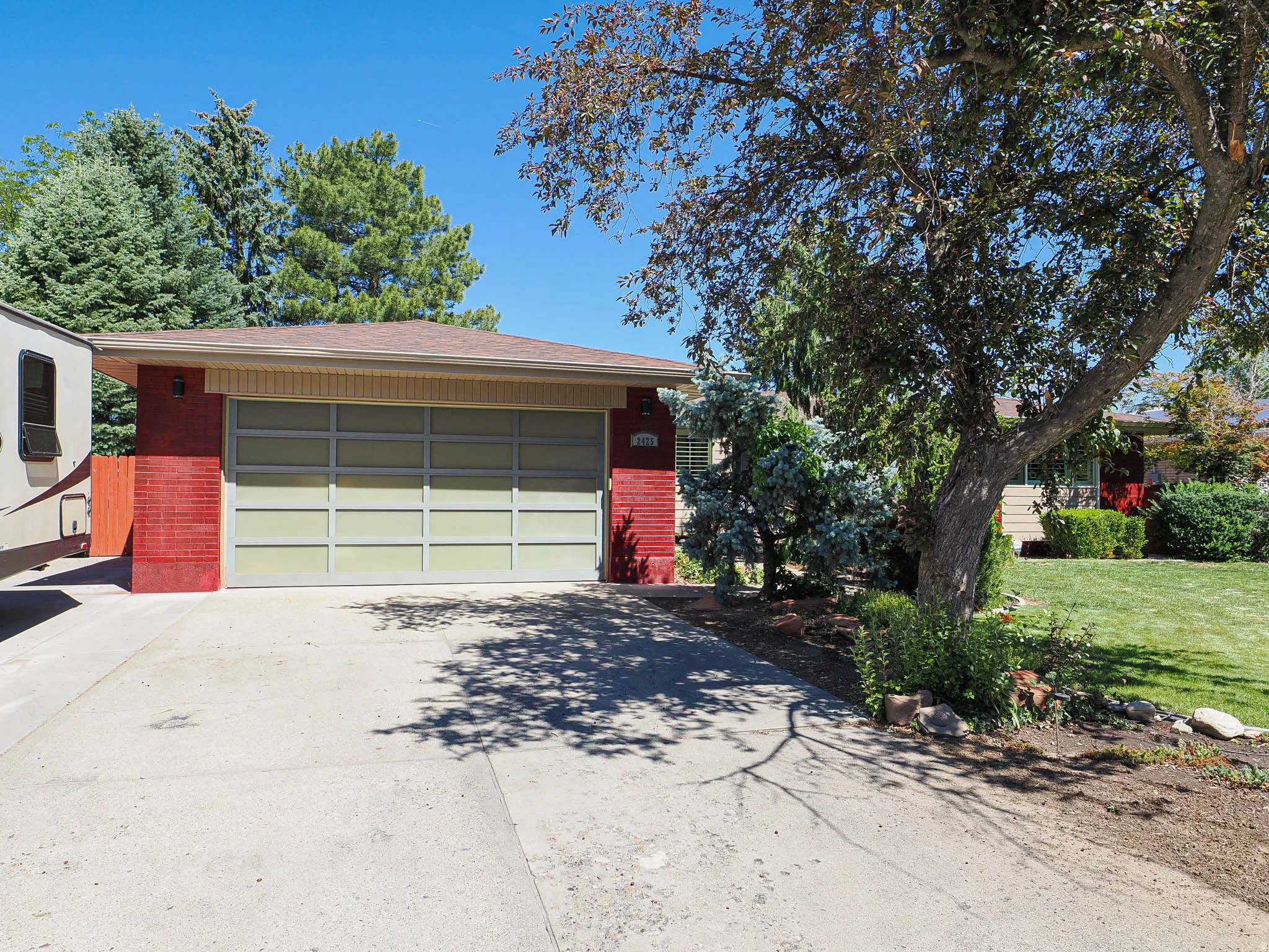 Red brick facade with a contemporary garage door and concrete driveway