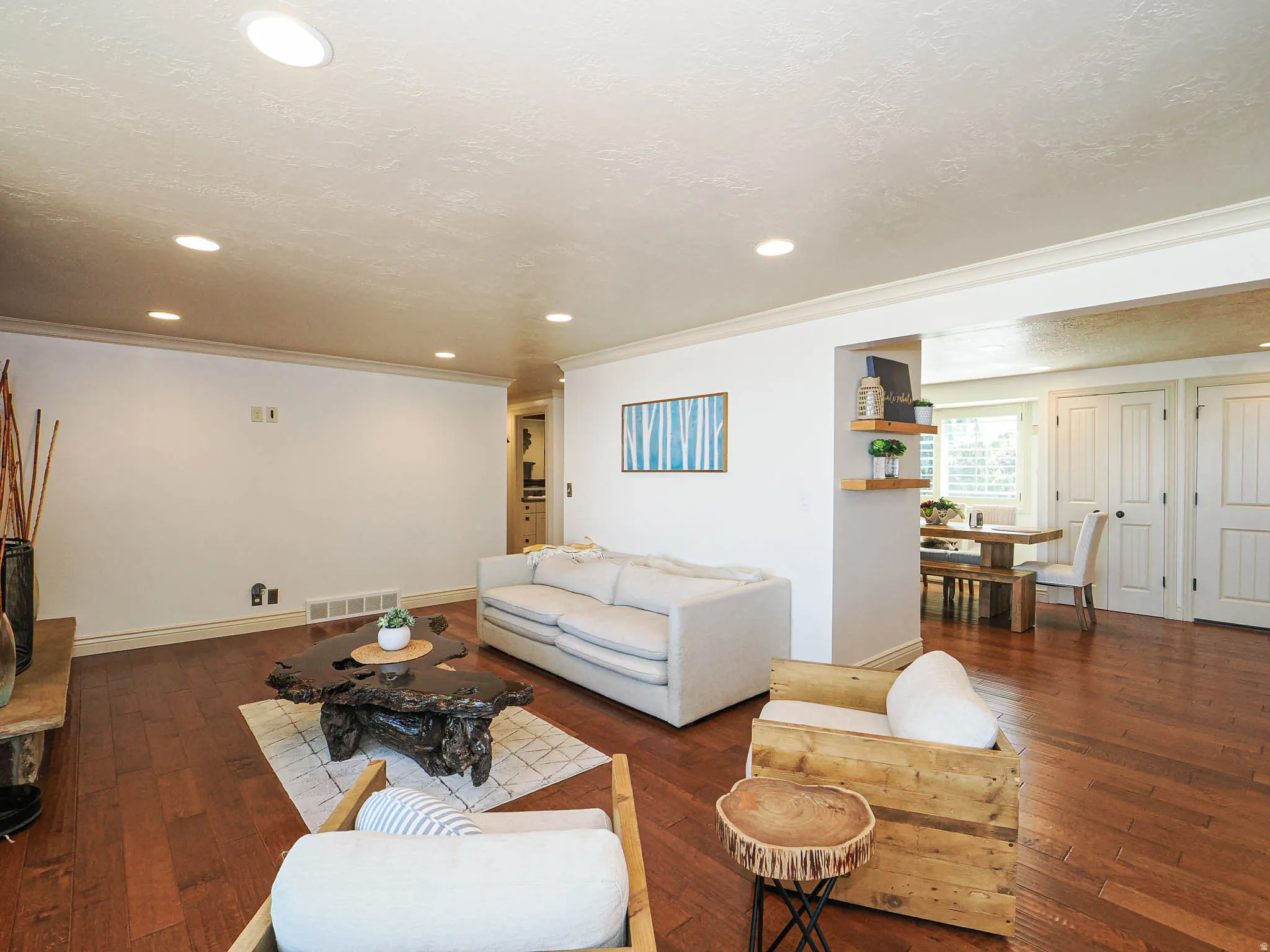 Living area featuring wood-finish flooring, recessed lighting, white crown molding, and a wide entryway to an adjacent dining space