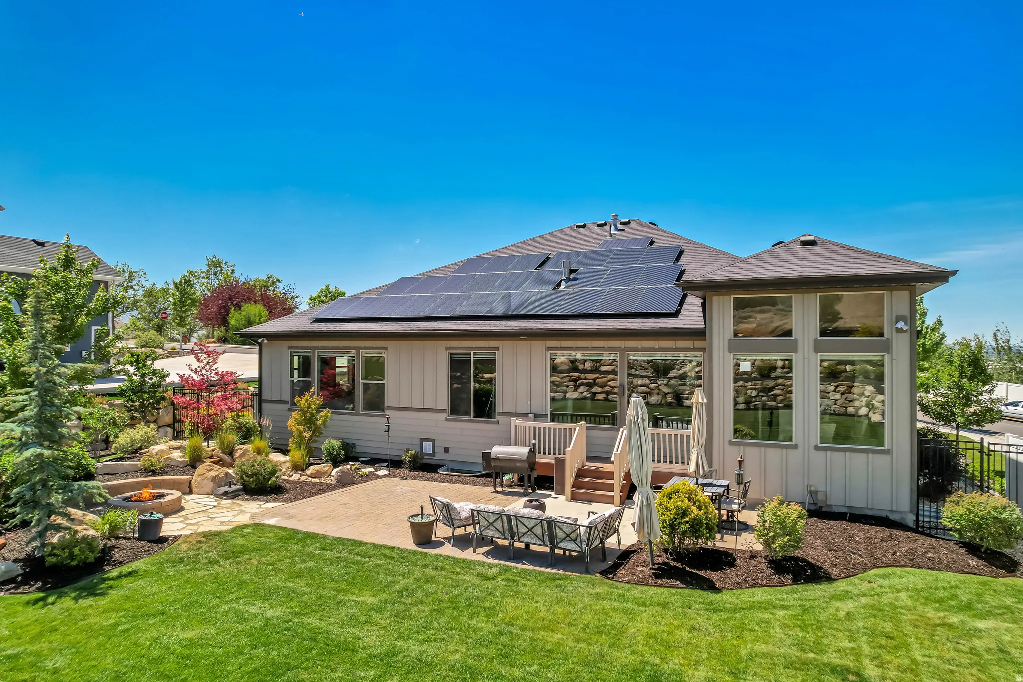 Expansive backyard featuring a manicured lawn, a large paver patio, and a dedicated fire pit area