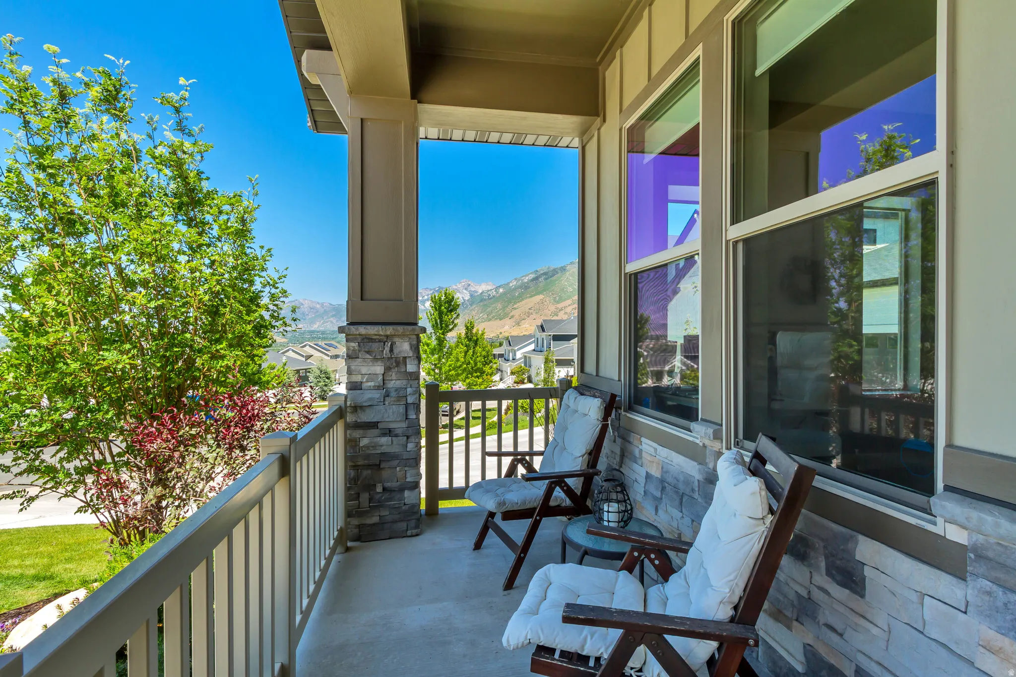Covered front porch featuring a stone veneer base, painted railing, and vertical siding