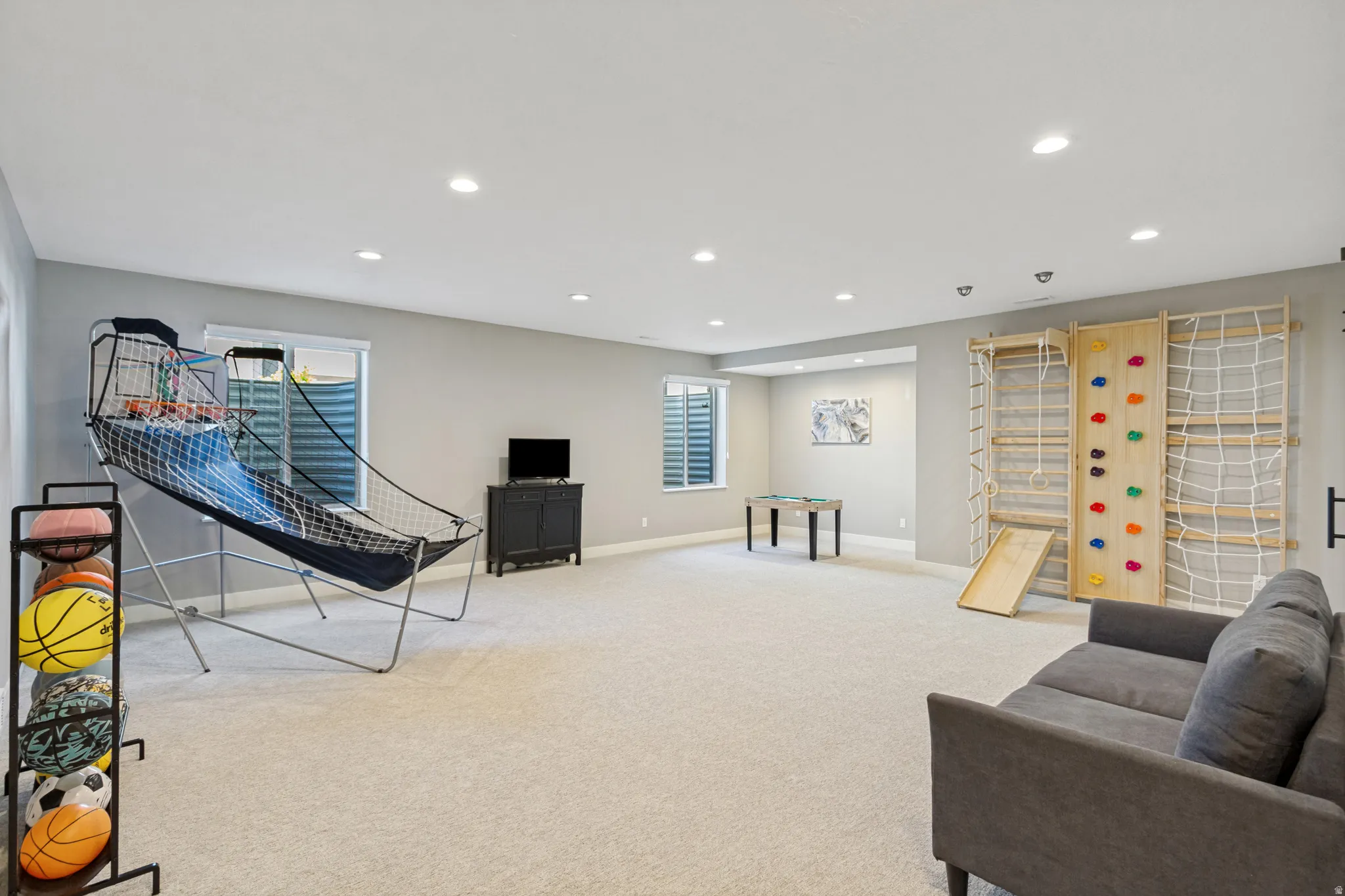 Spacious recreation room featuring recessed lighting, light-toned carpeting, and a built-in climbing wall with a slide