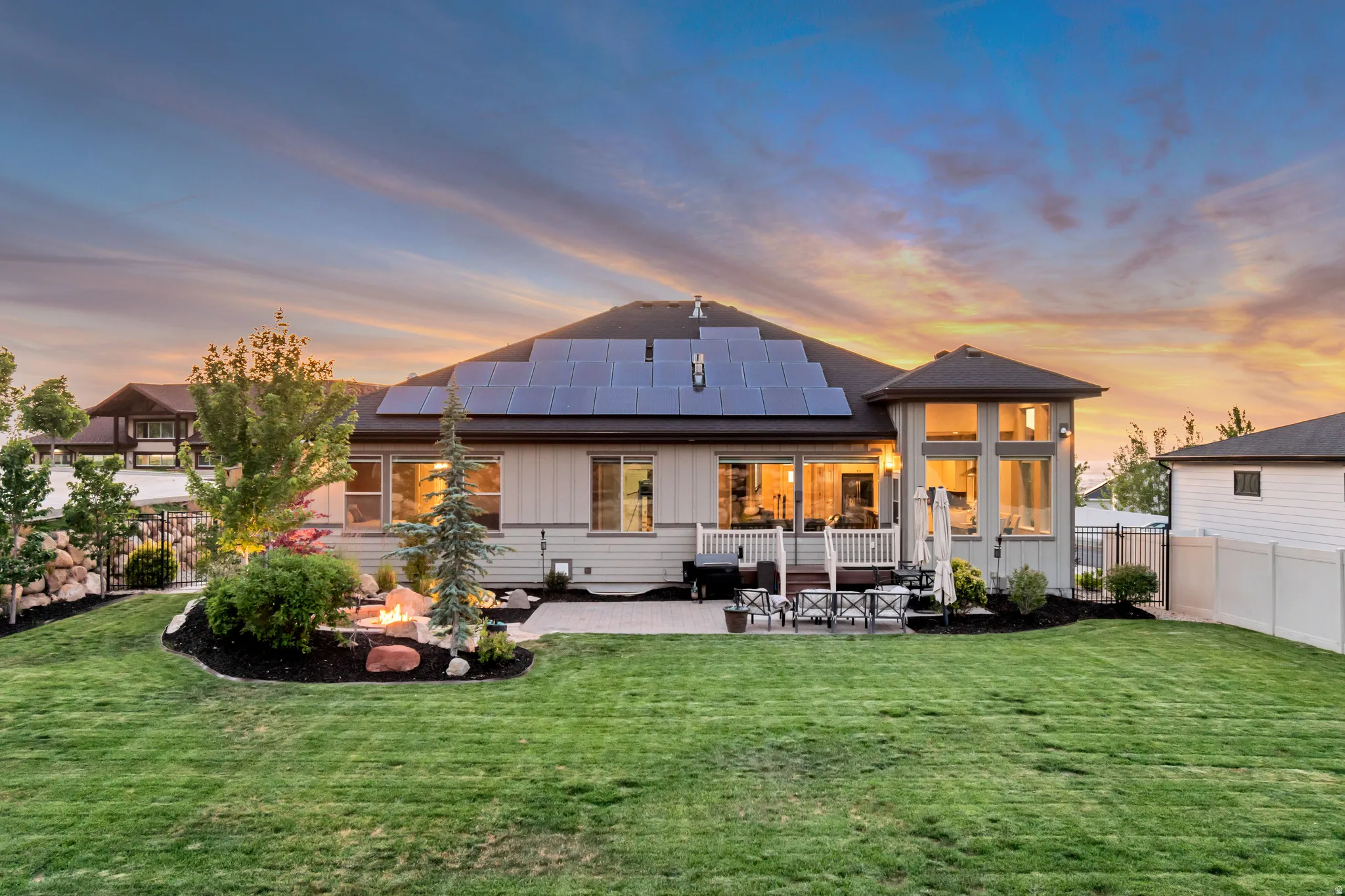 Expansive backyard featuring a stone fire pit, extensive patio area, and built-in solar panels