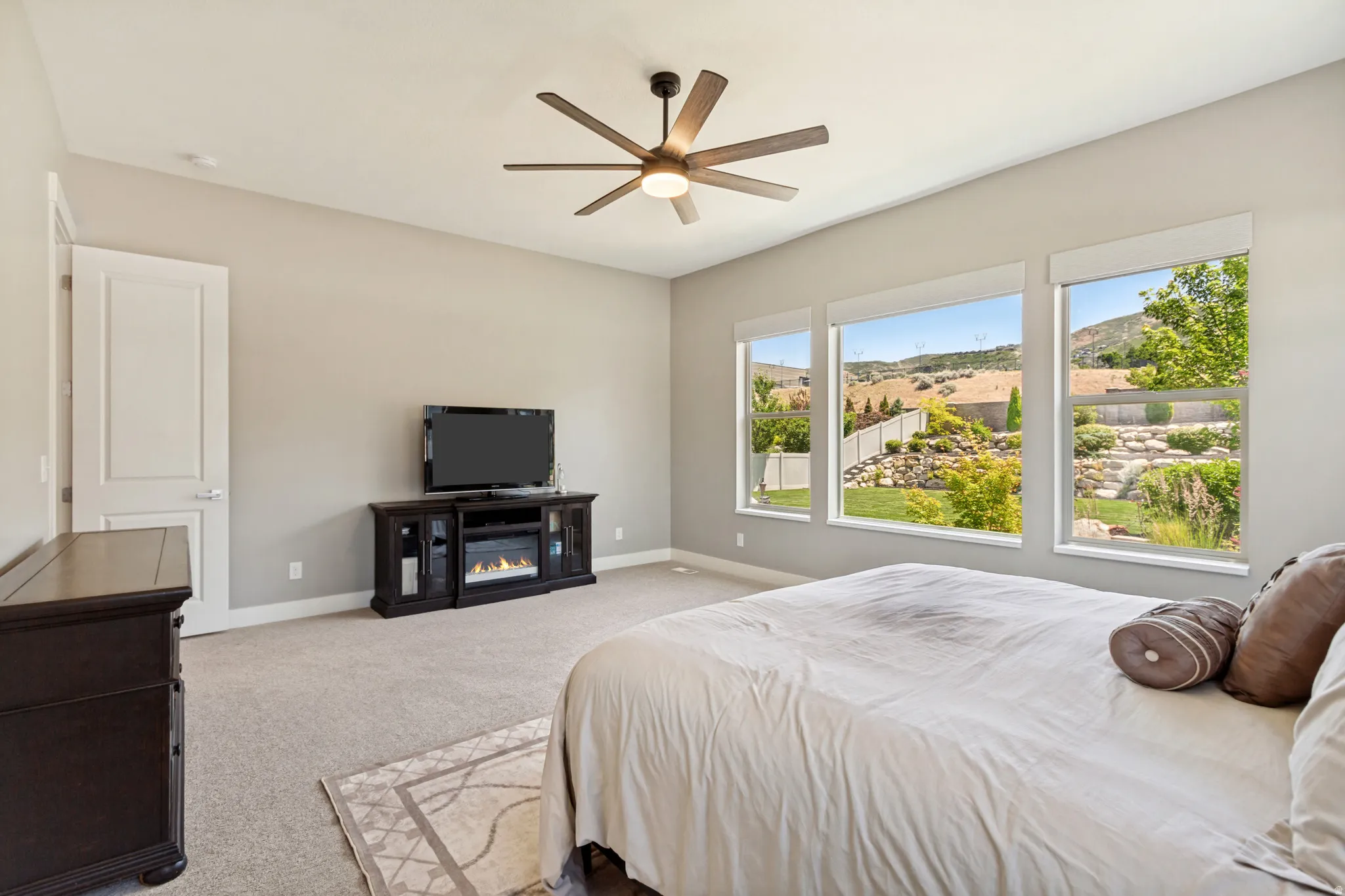 Spacious room featuring three large picture windows, sloped ceiling, and a ceiling fan with light fixture