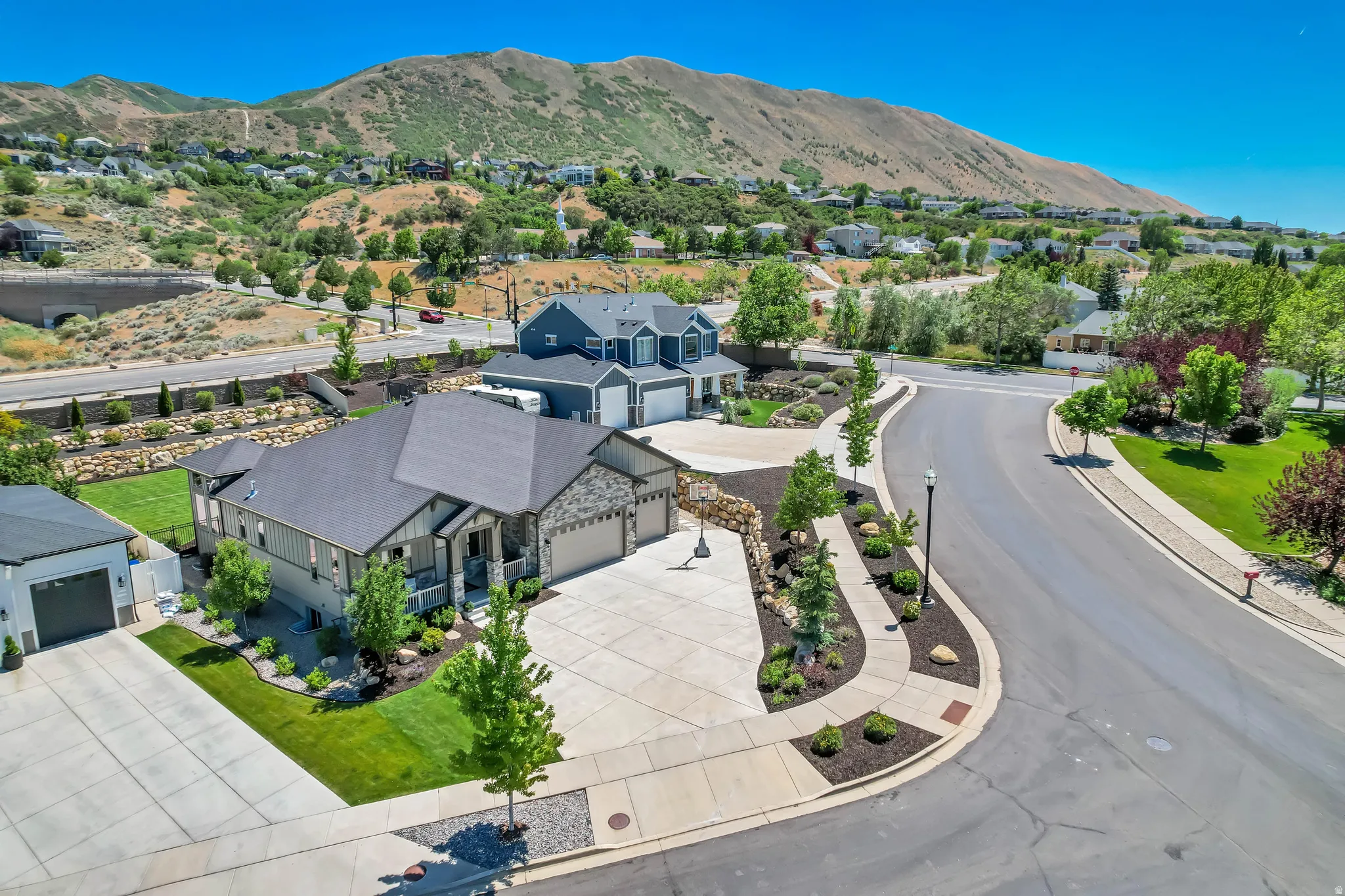 Contemporary residence featuring a dark gray roof, light-toned siding, and stone accents