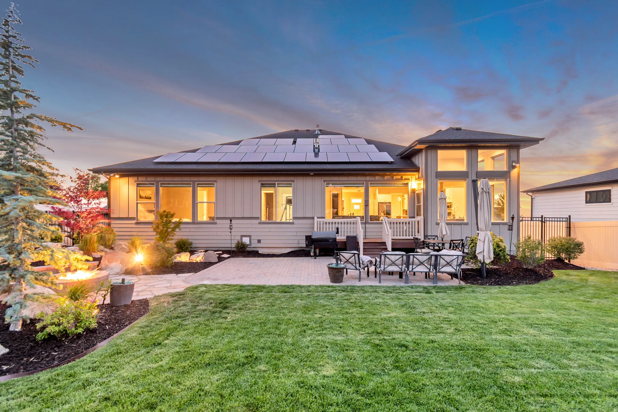 Expansive backyard with a manicured lawn, a large paver patio, and a dedicated fire pit area